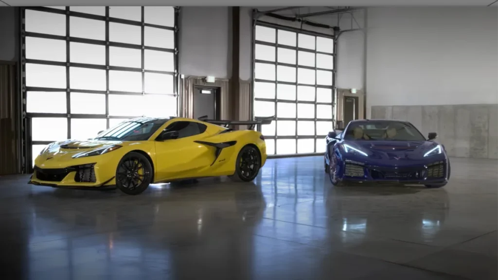 Two high-performance sports cars, one yellow and one blue, parked side by side in an industrial-style garage with a large windowed door in the background.