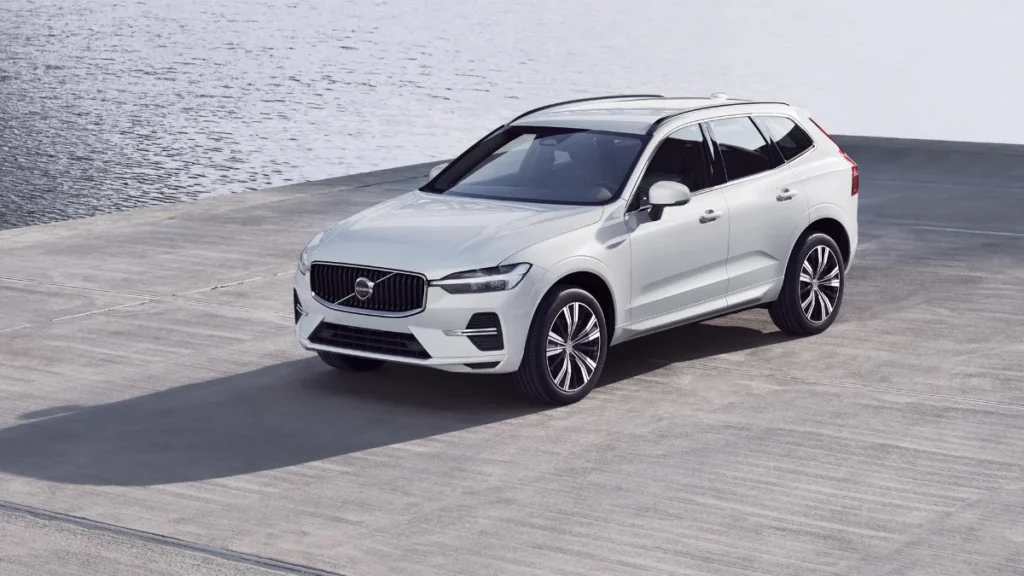 A white Volvo XC60 SUV parked on a concrete dock next to calm waters.